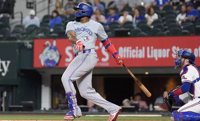 Toronto Blue Jays' Vladimir Guerrero Jr. follows through on a single as Texas Rangers catcher Jonah Heim looks on in the first inning of a baseball game in Arlington, Texas, Tuesday, Sept. 17, 2024. (AP Photo/Tony Gutierrez)