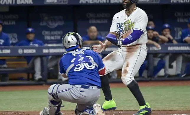 Toronto Blue Jays catcher Alejandro Kirk (30) tags out Tampa Bay Rays' Yandy Díaz, right, at the plate on a fielder's choice to Toronto first baseman Vladimir Guerrero Jr. during the third inning of a baseball game Friday, Sept. 20, 2024, in St. Petersburg, Fla. (AP Photo/Steve Nesius)