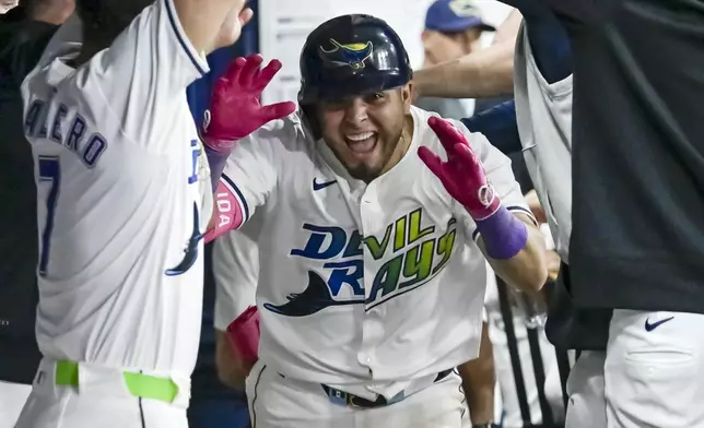 Tampa Bay Rays teammates celebrate with Jonathan Aranda, center, in the dugout after his solo home sixth nning of a baseball game Friday, Sept. 20, 2024, in St. Petersburg, Fla. (AP Photo/Steve Nesius)