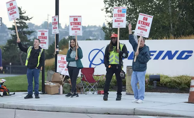 Boeing Machinists Union members from left, Brent Roberts, Ha Nguyen, Myles Simms and Rich Russell, wave to passing traffic while on the picket line at the Renton assembly plant, Friday, Sept. 13, 2024, in Renton, Wash. (AP Photo/John Froschauer)