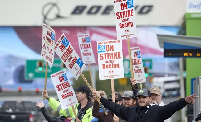 Boeing Machinists Union member Nico Padilla, front, and others wave to passing traffic on the picket line at the Everett plant, Friday, Sept. 13, 2024, in Everett, Wash. (AP Photo/John Froschauer)