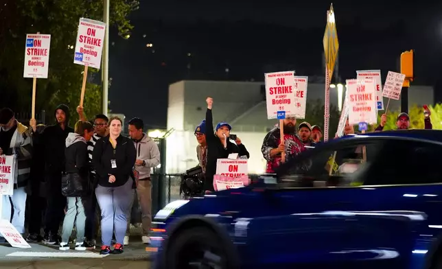 Boeing workers wave at a car honking in support while they picket after union members voted overwhelmingly to reject a contract offer and go on strike Friday, Sept. 13, 2024, in Renton, Wash. (AP Photo/Lindsey Wasson)