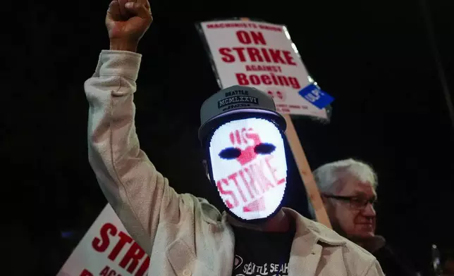 A Boeing worker wears a mask with a digital "strike" sign as employees picket after union members voted overwhelmingly to reject a contract offer and go on strike Friday, Sept. 13, 2024, outside the company's factory in Renton, Wash. (AP Photo/Lindsey Wasson)