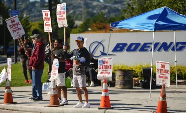 Boeing employees Cham Sin, in black, and Lou Saephanh, right center, wave signs as Boeing workers continue to strike Tuesday, Sept. 24, 2024, near the company's factory in Renton, Wash. (AP Photo/Lindsey Wasson)