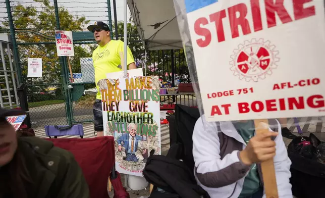 Daniel Dias, a functional test technician who has worked for Boeing for six years, back center, stands near an entrance to the company's factory as workers hold picket signs while striking Tuesday, Sept. 24, 2024, in Renton, Wash. (AP Photo/Lindsey Wasson)