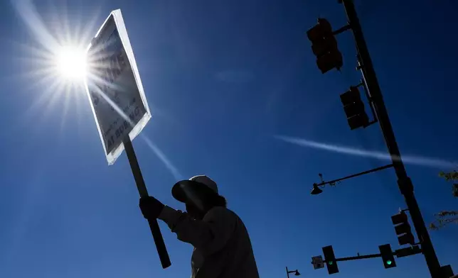 Boeing employee Som Dom, an electrician who has worked 17 years at Renton factory, holds a picket sign as workers strike Tuesday, Sept. 24, 2024, outside the company's factory in Renton, Wash. (AP Photo/Lindsey Wasson)