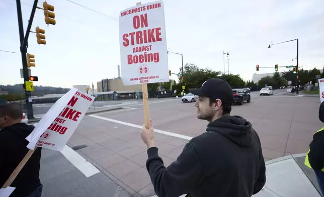 Boeing Machinists Union member Andrei Cojocaru waves at passing traffic from the picket line at the Renton assembly plant, Friday, Sept. 13, 2024, in Renton, Wash. (AP Photo/John Froschauer)