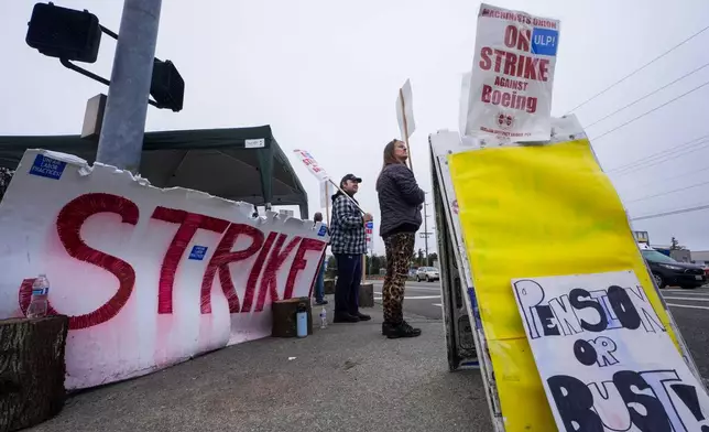 Denise Strike, a 13-year employee of Boeing, right, waves picket signs with 10-year employee Jacob Larson, left, as they strike after union members voted to reject a contract offer, Sunday, Sept. 15, 2024, near the company's factory in Everett, Wash. (AP Photo/Lindsey Wasson)