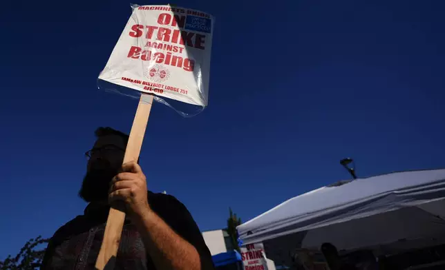 A Boeing worker waves a picket sign Tuesday, Sept. 24, 2024, as workers continue to strike outside the company's factory in Renton, Wash. (AP Photo/Lindsey Wasson)