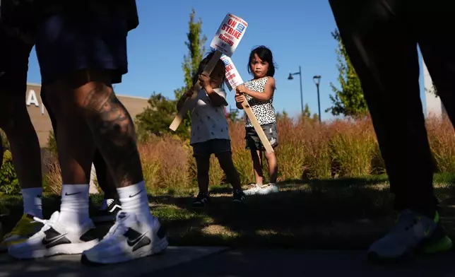 Accompanying their father, who works for Boeing, Kassie Odo 2, and Iya Odo, 4, hold small picket signs, Tuesday, Sept. 24, 2024, as Boeing workers strike near the company's factory in Renton, Wash. (AP Photo/Lindsey Wasson)