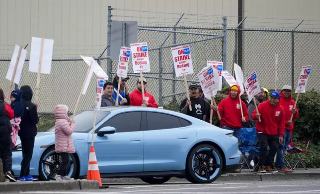 Boeing workers boo a car turning into the Everett factory parking lot as they wave picket signs while striking after union members voted to reject a contract offer, Sunday, Sept. 15, 2024, near the company's factory in Everett, Wash. (AP Photo/Lindsey Wasson)