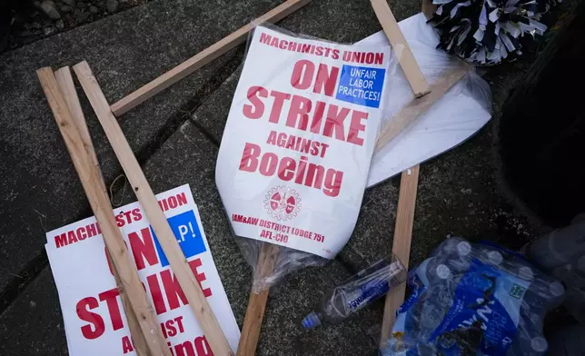 Extra picket signs sit on the sidewalk as Boeing workers strike after union members voted to reject a contract offer, Sunday, Sept. 15, 2024, near the company's factory in Everett, Wash. (AP Photo/Lindsey Wasson)