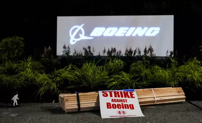 Signs and firewood sit in front of a Boeing sign as employees picket after union members voted overwhelmingly to reject a contract offer and go on strike Friday, Sept. 13, 2024, outside the company's factory in Renton, Wash. (AP Photo/Lindsey Wasson)