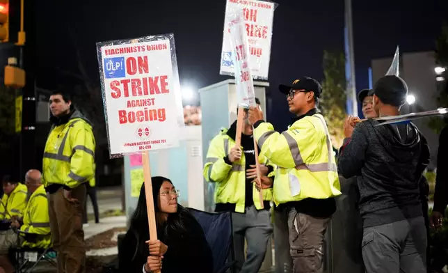 Boeing employee Dianna Vu, 20, a grade 6 mechanic, holds a picket sign with coworkers after union members voted overwhelmingly to reject a contract offer and go on strike Friday, Sept. 13, 2024, outside the company's factory in Renton, Wash. (AP Photo/Lindsey Wasson)