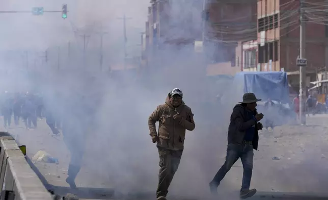 Supporters of former President Evo Morales run from tear gas thrown by police during clashes with supporters of current President Luis Arce, in El Alto, Bolivia, Sunday, Sept. 22, 2024. (AP Photo/Juan Karita)