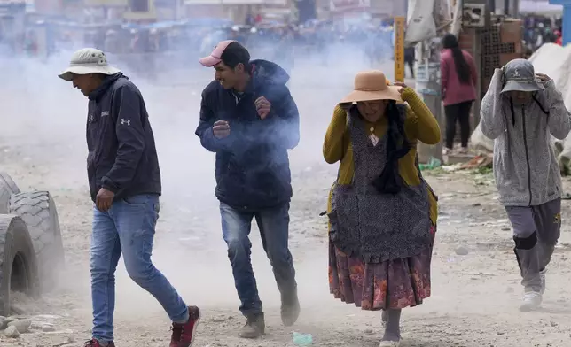 Supporters of former President Evo Morales run from tear gas thrown by police during clashes with supporters of current President Luis Arce in El Alto, Bolivia, Sunday, Sept. 22, 2024. (AP Photo/Juan Karita)