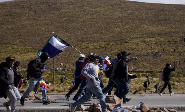 Supporters of former President Evo Morales, who are marching to the capital to protest the government of current President Luis Arce, run towards Arce supporters who met them along the route in Vila Vila, Bolivia, Tuesday, Sept. 17, 2024. (AP Photo/Juan Karita)