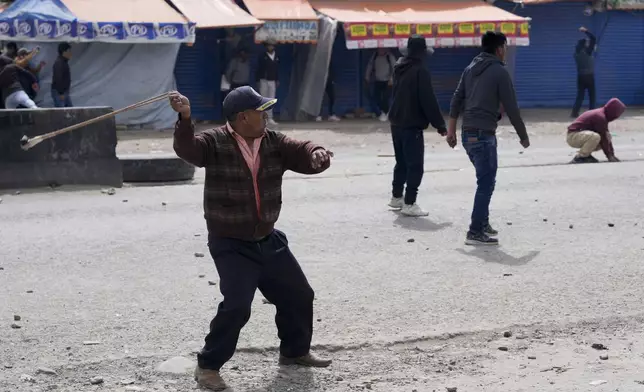 A supporter of former President Evo Morales slings a rock at supporters of current President Luis Arce in El Alto, Bolivia, Sunday, Sept. 22, 2024. (AP Photo/Juan Karita)