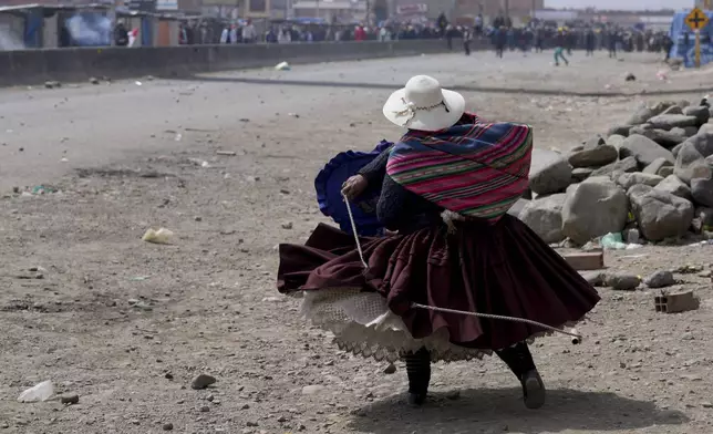 A supporter of former President Evo Morales throws a rock at supporters of current President Luis Arce in El Alto, Bolivia, Sunday, Sept. 22, 2024. (AP Photo/Juan Karita)