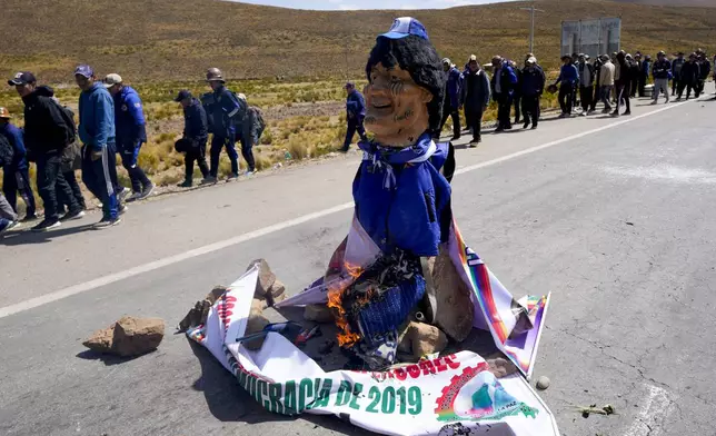 An effigy of former President Evo Morales starts to burn on a road between Caracollo and La Paz, to block Morales supporters who are marching to the capital against the government of President Luis Arce in an escalation of a political dispute between the two politicians, Tuesday, Sept. 17, 2024. (AP Photo/Juan Karita)