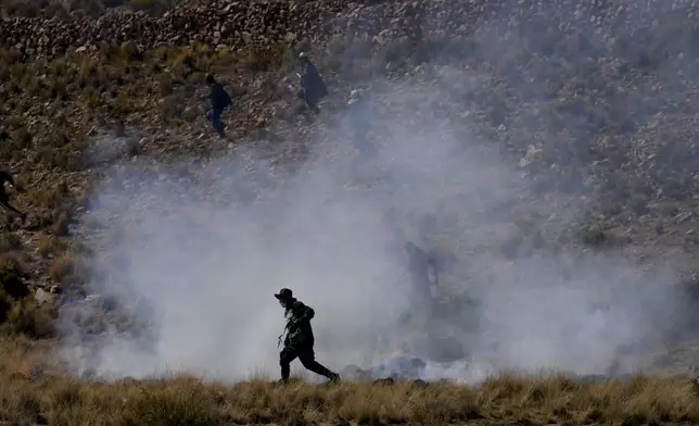 A government supporter runs through tear gas during clashes with supporters of former President Evo Morales who are marching to the capital to protest the government of current President Luis Arce in Vila Vila, Bolivia, Tuesday, Sept. 17, 2024. (AP Photo/Juan Karita)