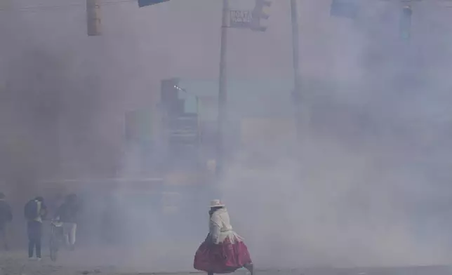 A woman runs through tear gas thrown by police during clashes between supporters of former President Evo Morales and current President Luis Arce in El Alto, Bolivia, Sunday, Sept. 22, 2024. (AP Photo/Juan Karita)