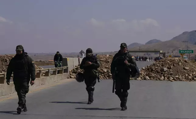 Police patrol at a roadblock in Vilaque on the outskirts of El Alto, Bolivia, Monday, Sept. 16, 2024. The roadblock was placed by protesters demanding the resignation of Bolivian President Luis Arce for his management of the economy. (AP Photo/Juan Karita)