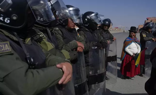 Police keep protesters from blocking more lanes as they protest for the resignation of Bolivian President Luis Arce for his management of the economy in Corapata, on the outskirts of El Alto, Bolivia, Monday, Sept. 16, 2024. (AP Photo/Juan Karita)