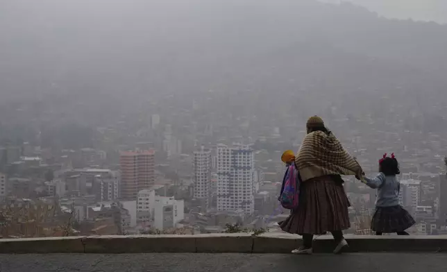 A woman walks her daughter to school amid smoke from wildfires in La Paz, Bolivia, Monday, Sept. 9, 2024. (AP Photo/Juan Karita)