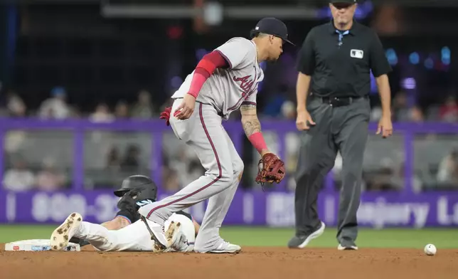 Miami Marlins' Connor Norby (24) slides into second base as Atlanta Braves shortstop Orlando Arcia (11) drops the ball during the fifth inning of a baseball game, Friday, Sept. 20, 2024, in Miami. (AP Photo/Marta Lavandier)