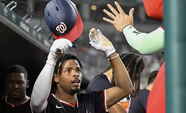 Washington Nationals' Jose Tena is congratulated by teammates in the dugout after scoring a run during the eighth inning of a baseball game against the Atlanta Braves, Wednesday, Sept. 11, 2024, in Washington. (AP Photo/John McDonnell)