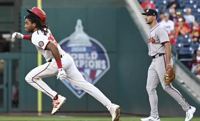 Washington Nationals' James Wood, left, runs past Atlanta Braves first baseman Matt Olson on a double during the first inning of a baseball game, Tuesday, Sept. 10, 2024, in Washington. (AP Photo/John McDonnell)