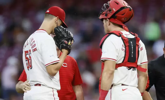 Cincinnati Reds starting pitcher Brandon Williamson, left, talks with catcher Tyler Stephenson and a trainer before being taken out of the game with an injury against the Atlanta Braves during the second inning of a baseball game Tuesday, Sept. 17, 2024, in Cincinnati. (AP Photo/Jay LaPrete)