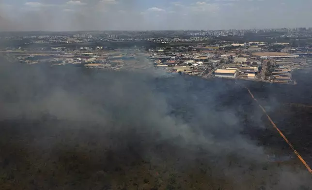 Smoke rises from a fire in the environmentally protected area of Brasilia National Park during the dry season in Brasilia, Brazil, Monday, Sept. 16, 2024. The head of the agency that manages protected areas, Mauro Pires, told the local press that the fire was man-made and appears to have started near the edge of the presidency's official countryside residence. (AP Photo/Eraldo Peres)