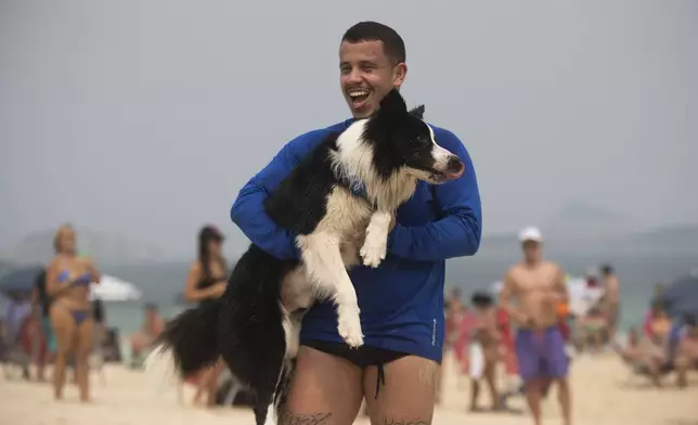 Coach Gustavo Rodrigues celebrates a point with his trainee, border collie named Floki, as they play footvolley, a combination of soccer and volleyball, on Leblon beach in Rio de Janeiro, Sunday, Sept. 8, 2024. (AP Photo/Bruna Prado)