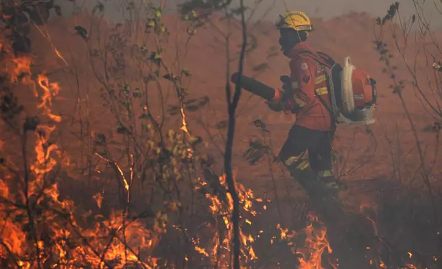 A firefighter attempts to put out a forest fire spreading in the environmentally protected area of Brasilia National Park during the dry season in Brasilia, Brazil, Monday, Sept. 16, 2024. Mauro Pires, the head of the agency that manages protected areas, told the local press that the fire is man-made and appears to have started near the edge of the presidency's official countryside residence. (AP Photo/Eraldo Peres)