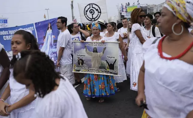 A woman holds a sign that reads "Indigenous people, Black people, we are all equal before Christ" during the Defense of Religious Freedom march at Copacabana beach in Rio de Janeiro, Sunday, Sept. 15, 2024. The march seeks to bring attention to religious intolerance in the country. (AP Photo/Silvia Izquierdo)