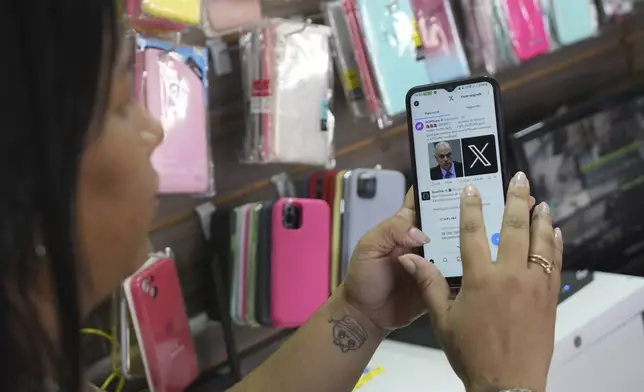 Ana Claudia, a salesperson at a cell phone case store located inside the bus station, shows the last X post she received before the social media platform was blocked nationwide in Brasilia, Brazil, Monday, Sept. 2, 2024. (AP Photo/Eraldo Peres)