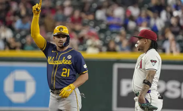 Milwaukee Brewers' Willy Adames, left, celebrates his double in front of Arizona Diamondbacks second base Ketel Marte during the sixth inning of a baseball game, Sunday, Sept. 15, 2024, in Phoenix. (AP Photo/Darryl Webb)