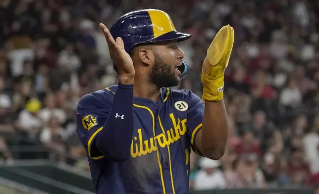 After scoring a run, Milwaukee Brewers' Brice Turang applauds Willy Adames' double during the sixth inning of a baseball game against the Arizona Diamondbacks, Sunday, Sept. 15, 2024, in Phoenix. (AP Photo/Darryl Webb)