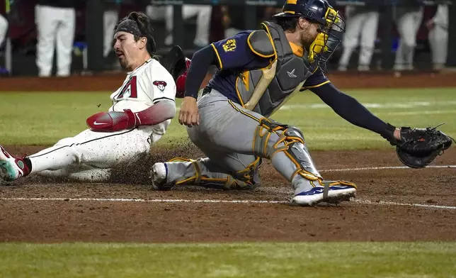 Arizona Diamondbacks' Corbin Carroll, left, slides into home behind Milwaukee Brewers catcher Eric Haase, right, during the eighth inning of a baseball game, Sunday, Sept. 15, 2024, in Phoenix. (AP Photo/Darryl Webb)