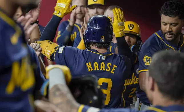 Milwaukee Brewers' Eric Haase, center, gets high-fives after hitting a home run against the Arizona Diamondbacks during the sixth inning of a baseball game, Sunday, Sept. 15, 2024, in Phoenix. (AP Photo/Darryl Webb)