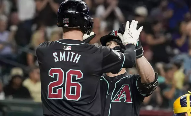 Arizona Diamondbacks' Pavin Smith (26) greets Randal Grichuk, right, at home plate after Grichuk's two-run home run against the Milwaukee Brewers during the seventh inning of a baseball game, Saturday, Sept. 14, 2024, in Phoenix. (AP Photo/Darryl Webb)