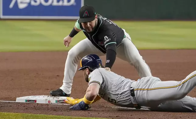 Arizona Diamondbacks third base Eugenio Suárez, top, tags out Milwaukee Brewers' Garrett Mitchell, bottom, after a steal-attempt during the first inning of a baseball game, Saturday, Sept. 14, 2024, in Phoenix. (AP Photo/Darryl Webb)