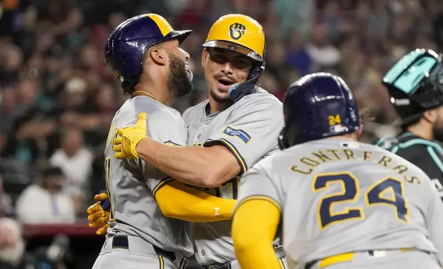 Milwaukee Brewers' Willy Adames, center, is congratulated by Jackson Chourio, left, and William Contreras (24) after hitting a grand slam against the Arizona Diamondbacks during the second inning of a baseball game, Saturday, Sept. 14, 2024, in Phoenix. (AP Photo/Darryl Webb)