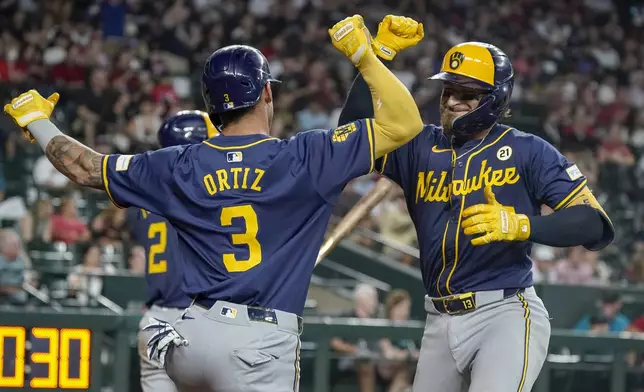 Milwaukee Brewers' Eric Haase, right, celebrates after his home run against the Arizona Diamondbacks with Joey Ortiz, left, during the sixth inning of a baseball game, Sunday, Sept. 15, 2024, in Phoenix. (AP Photo/Darryl Webb)