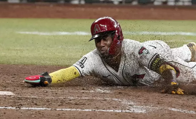 Arizona Diamondbacks' Geraldo Perdomo scores as he slides into home during the seventh inning of a baseball game against the Milwaukee Brewers, Sunday, Sept. 15, 2024, in Phoenix. (AP Photo/Darryl Webb)