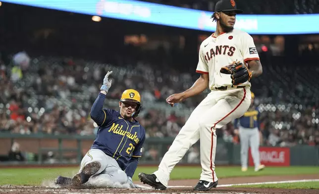 Milwaukee Brewers' Willy Adames, left, scores on a wild pitch by San Francisco Giants pitcher Camilo Doval during the seventh inning of a baseball game in San Francisco, Thursday, Sept. 12, 2024. (AP Photo/Kavin Mistry)