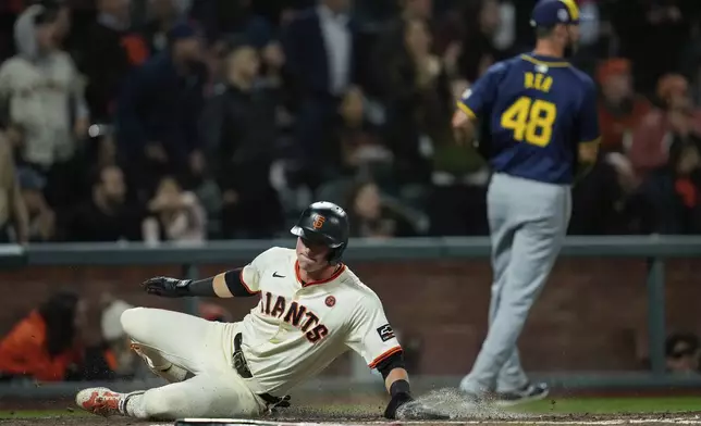 San Francisco Giants' Tyler Fitzgerald, left, scores on Mike Yastrzemski's double during the fourth inning of a baseball game against the Milwaukee Brewers, Wednesday, Sept. 11, 2024, in San Francisco. Yastrzemski was tagged out at third on the play. (AP Photo/Godofredo A. Vásquez)