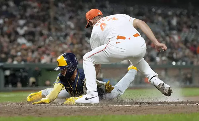 Milwaukee Brewers' Joey Ortiz, left, is tagged out at home plate by San Francisco Giants pitcher Tristan Beck as he tries to score from third on a wild pitch in the seventh inning of a baseball game, Tuesday, Sept. 10, 2024, in San Francisco. (AP Photo/Tony Avelar)